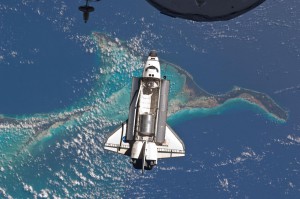 Space shuttle Atlantis is seen over the Bahamas prior to a perfect docking with the International Space Station at 10:07 a.m. (CDT). Part of a Russian Progress spacecraft which is docked to the station is in the foreground.