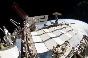 A portion of the International Space Station and the docked space shuttle Endeavour (left) are featured in this image photographed by a spacewalker, using a fish-eye lens attached to an electronic still camera, during the STS-134 mission's fourth session of extravehicular activity (EVA). Earth's horizon and the blackness of space provide the backdrop for the scene.