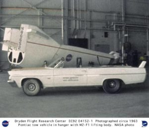 The M2-F1 in its hangar with NASA’s muscle car, the Pontiac Catalina convertible tow vehicle. Photo Credit: NASA