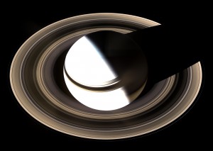 1aSaturn sits enveloped by the full splendor of its stately rings. Between the blinding light of day and the dark of night, there is a strip of twilight on the globe where colorful details in the atmosphere can be seen.  