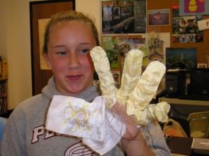 Alexis of Pemetic Elementary School tries on one of Peter Homer's “failed” glove designs.  