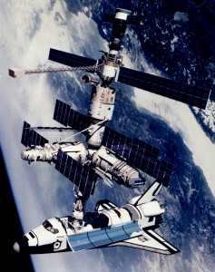 This is a technical rendition of the Space Shuttle Atlantis docked to the Kristall module of the Russian Mir Space Station. The configuration is that of STS-71/Mir Expedition 18, a joint U.S.–Russian mission completed in June 1995, and represents how having a common goal can help overcome project management and engineering challenges. 