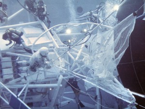 After Skylab’s launch, the large, delicate, meteoroid shield on the outside of the workshop was ripped off by the vibration of the launch. Engineers worked frantically to develop solutions to this and other problems and designed a protective solar sail to cover the workshop. Here astronauts practice deploying the protective solar sail in Marshall Space Flight Center’s Neutral Buoyancy Simulator. Astronauts Conrad and Kerwin were able to complete the needed repairs to Skylab, salvaging the entire program. 