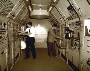 Astronauts Joseph Kerwin (left) and William Lenoir familiarize themselves with equipment aboard the Spacelab mockup during a 1976 visit to the Marshall Space Flight Center.