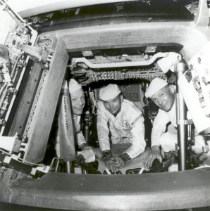 Peering from the Apollo 11 hatch while conducting a crew compartment fit and functional check in their command module are, from left, Neil Armstrong, commander; Michael Collins, command module pilot; and Buzz Aldrin, lunar module pilot. Lessons from Gemini and large-scale project management aided Project Apollo’s success.  