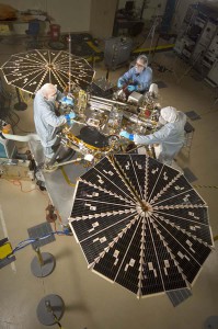 Spacecraft specialists work on the lander after its fan-like circular solar arrays have been spread open for testing. 
