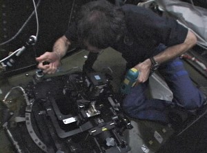 Donald Pettit using one camera to track city lights and taking the image with a second camera via a cable release. Amateur astronomers will recognize that what was improvised out of spare parts on the space station is no more than what they have been doing for decades with a simple tracking system dubbed a "barn door" that consists of two boards, a piano hinge, and a manually rotated bolt. The difference between handheld images of cities at night and those made with the tracking system is striking. 