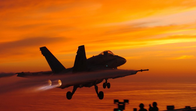 A Hornet launches at sunset aboard USS John C. Stennis