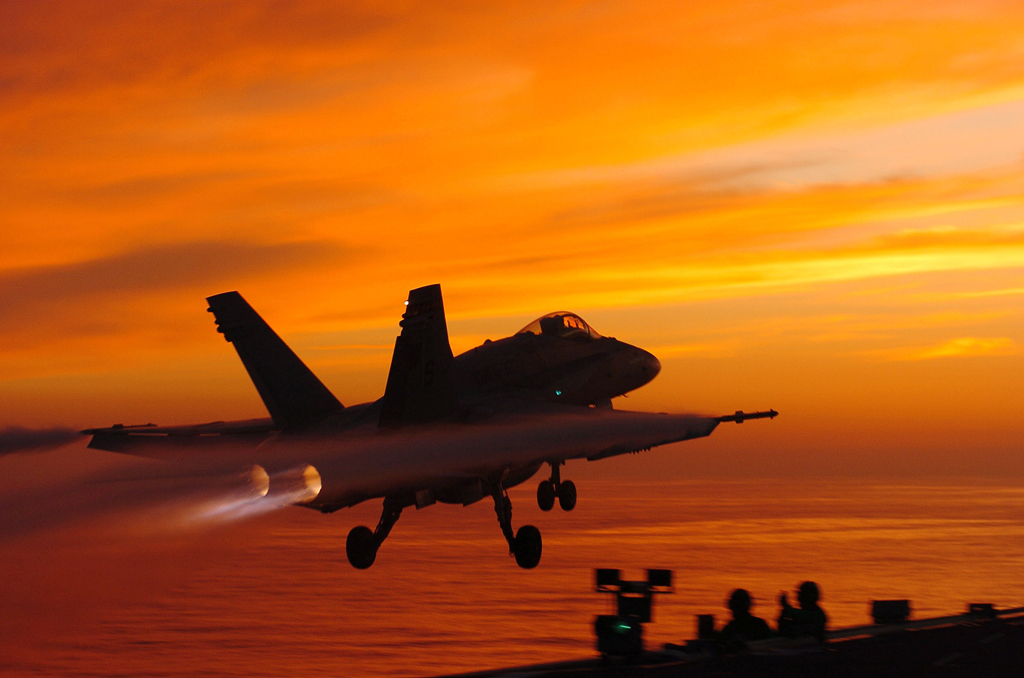 A Hornet launches at sunset aboard USS John C. Stennis