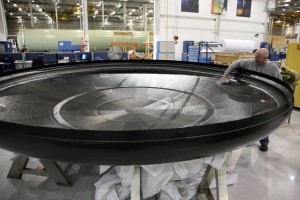 Inspecting the carbon-composite carrier structure for the first Dragon spacecraft heat shield, fresh from its mold. At nearly 4 m (13 ft.) in diameter, the structure supports the PICA-X tiles that protect the spacecraft during reentry. 
