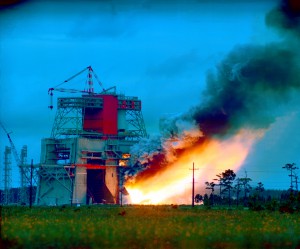 Smoke and flames belch from the huge S-1C test stand as the first stage booster of the Apollo/Saturn V space vehicle is static fired at the NASA Mississippi Test Facility, now Stennis Space Center. 