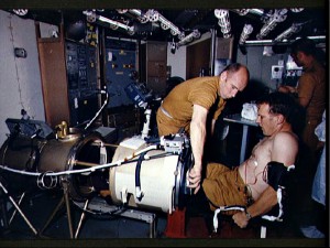 During a preview of Skylab medical altitude test experiments, Astronaut Karol J. Bobko is being configured for a test in the Lower Body Negative Pressure experiment while Scientist-Astronaut William E. Thornton assists. 