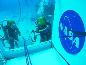 NASA Aquanaut crew performing demonstration of incapacitated crewman recovery on the side hatch of the SEV during the NEEMO 14 mission.