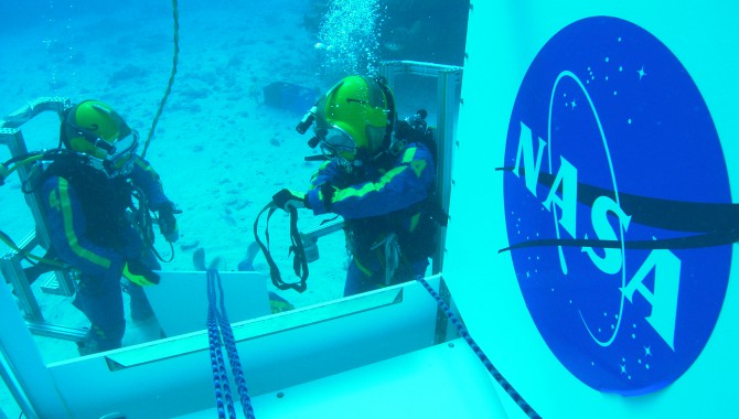 NASA Aquanaut crew performing demonstration of incapacitated crewman recovery on the side hatch of the SEV during the NEEMO 14 mission.