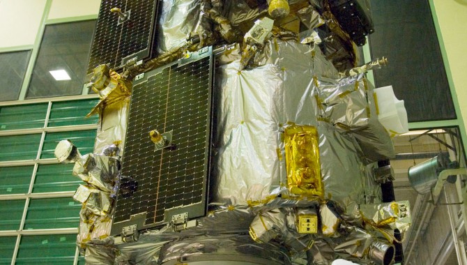 An engineer looks on as the stacked STEREO spacecraft undergo a spin balance test. Photo Credit: NASA