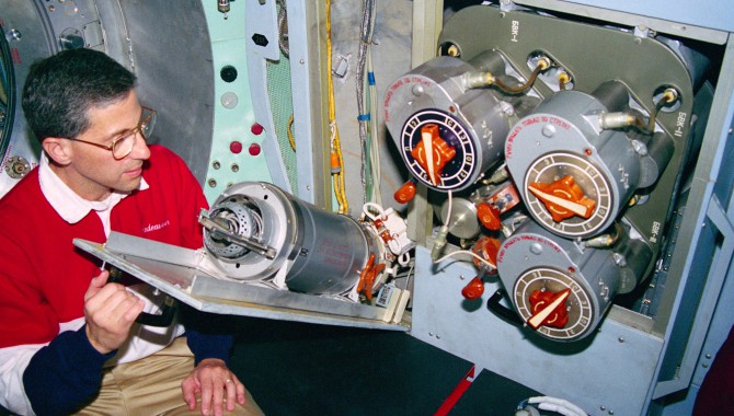 Astronaut Jay Apt looking at a solid-fuel oxygen generator like the one that caught fire on Mir.