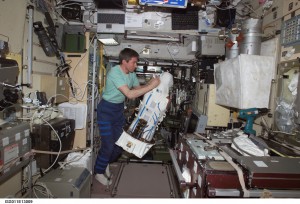Cosmonaut Sergei K. Krikalev works with the European Space Agency Matroshka radiation experiment in the Zvezda service module of the International Space Station. In the upper right of the foreground is the TGK backup oxygen system, with the ceramic mitigation screen in place.