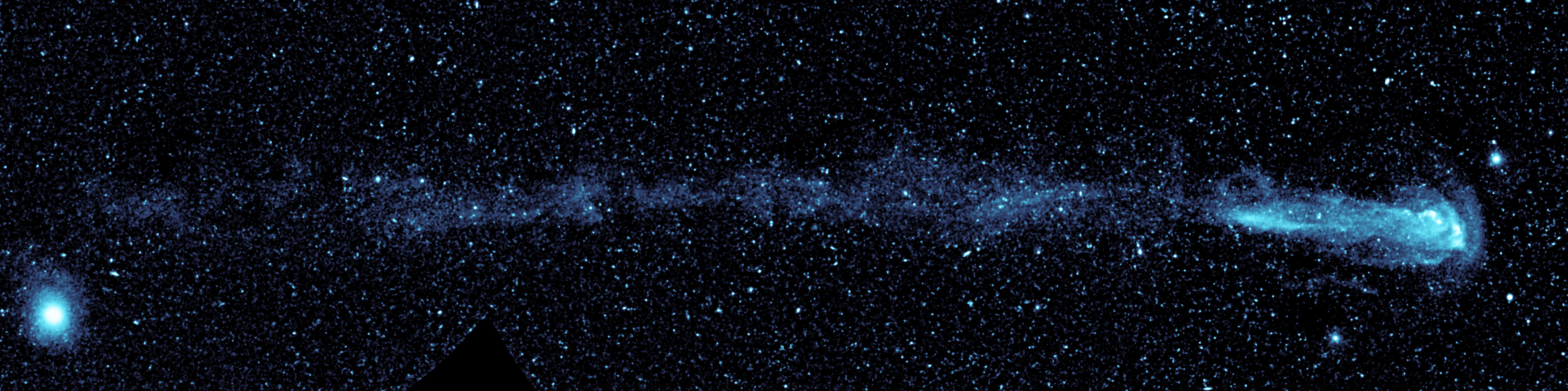 An ultraviolet mosaic from NASA’s Galaxy Evolution Explorer shows a speeding star that is leaving an enormous, 13-light-year-long trail. The star, named Mira (pronounced my-rah), appears as a small white dot in the bulb-shaped structure at right, and is moving from left to right in this view.