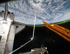 This panoramic view was photographed from the International Space Station toward Earth, looking past space shuttle Atlantis' docked cargo bay and part of the station, including a solar array panel. The photo was taken as the joint complex passed over the southern hemisphere. Aurora Australis or the Southern Lights can be seen on Earth's horizon and a number of stars also are visible.