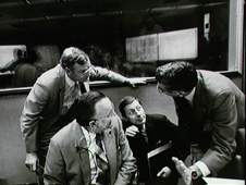 Major General J.A. Abrahamson, right, talks to JSC Director Christopher C. Kraft, Jr., (seated left) and Space Shuttle Program Manager Glynn S. Lunney on the back row of consoles in the mission operations control room (MOCR) in the Johnson Space Center mission control center. Abrahamson, second right, talks to JSC's Aaron Cohen, right, as Kraft (seated left) and Lunney listen in mission control.