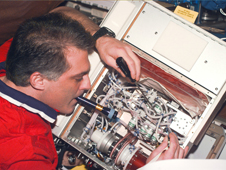Astronaut David Wolf performs maintenance on a NASA bioreactor unit onboard the Mir space station. Experiments conducted by Wolf demonstrated that the bioreactor produces even more effective cell-growth results in space.