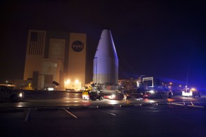 Tracking and Data Relay Satellite-K, enclosed in its payload fairing, passes through the Launch Complex 39 area and Vehicle Assembly Building at Kennedy Space Center as it travels from the Astrotech payload processing facility to its launch site.