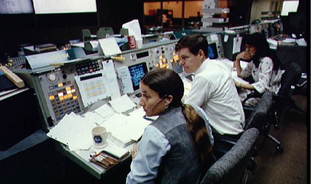 Astronauts Mary L. Cleve and Bryan D. O'Connor look toward the camera during an integrated simulation for the STS-6 mission. The two are at the spacecraft communicator (CAPCOM) console in the mission operations control room (MOCR) of the JSC mission control center.
