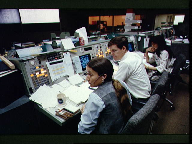 Astronauts Mary L. Cleve and Bryan D. O'Connor look toward the camera during an integrated simulation for the STS-6 mission. The two are at the spacecraft communicator (CAPCOM) console in the mission operations control room (MOCR) of the JSC mission control center.