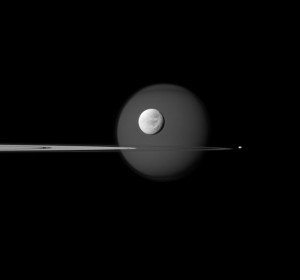 Saturn's largest moon, Titan, is in the background of the image, and the moon's north polar hood is clearly visible. See PIA08137 to learn more about that feature on Titan (3,200 miles, or 5,150 kilometers across). Next, the wispy terrain on the trailing hemisphere of Dione (698 miles, or 1,123 kilometers across) can be seen on that moon which appears just above the rings at the center of the image. See PIA10560 and PIA06163 to learn more about Dione's wisps. Saturn's small moon Pandora (50 miles, or 81 kilometers across) orbits beyond the rings on the right of the image. Finally, Pan (17 miles, or 28 kilometers across) can be seen in the Encke Gap of the A ring on the left of the image. The image was taken in visible blue light with the Cassini spacecraft narrow-angle camera on Sept. 17, 2011.