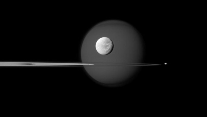 Saturn's largest moon, Titan, is in the background of the image, and the moon's north polar hood is clearly visible. See PIA08137 to learn more about that feature on Titan (3,200 miles, or 5,150 kilometers across). Next, the wispy terrain on the trailing hemisphere of Dione (698 miles, or 1,123 kilometers across) can be seen on that moon which appears just above the rings at the center of the image. See PIA10560 and PIA06163 to learn more about Dione's wisps. Saturn's small moon Pandora (50 miles, or 81 kilometers across) orbits beyond the rings on the right of the image. Finally, Pan (17 miles, or 28 kilometers across) can be seen in the Encke Gap of the A ring on the left of the image. The image was taken in visible blue light with the Cassini spacecraft narrow-angle camera on Sept. 17, 2011.