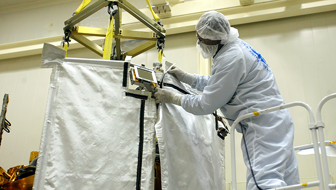 The middle section of the ceramic-cloth sunshade is being attached to MESSENGER. Photo Credit: NASA/Johns Hopkins University Applied Physics Laboratory/Carnegie Institution of Washington.