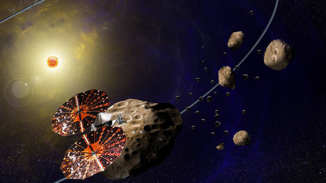 Artist's concept of the Lucy spacecraft flying past several of Jupiter's Trojan asteroids, which are early remnants of planetary formation in the solar system.