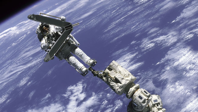 Crew member Lee M. E. Morin participated in his first extravehicular activity (EVA) during STS-110. Here, he is anchored to the station’s robotic arm, Canadarm2, which was used for the first time to move astronauts during EVAs. Photo Credit: NASA