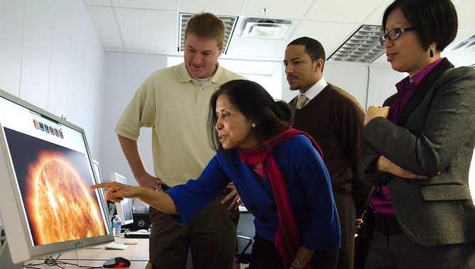 Group of men and women looking at a computer screen displaying an image of the Sun. Credit: NASA