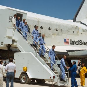 Mission Operations Director George W.S. Abbey, right, shakes hands with Astronaut C. Gordon Fullerton, as the crew of STS-51-F descends. Other crewmembers egressing the spacecraft are, left to right, F. Story Musgrave, John-David Bartoe, Roy D. Bridges, Jr., Karl J. Henize, Loren W. Acton, and Anthony W. England. Credit: NASA