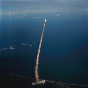 An air-to-air view of the Space Shuttle orbiter Challenger, its two solid rocket boosters and external fuel tank moments after launch from Pad 39A at Kennedy Space Center (KSC). Astronaut John W. Young, veteran of two Shuttle flights and four other NASA missions, took the photograph with a handheld camera while piloting the Shuttle training aircraft. Credit: NASA/John Young