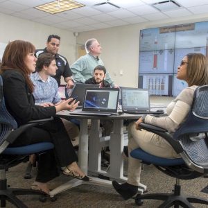 Group of people sitting at desks in an office setting. Credit: NASA