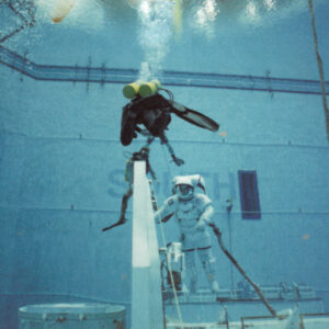 Jim Sarafin is diving with an astronaut. The astronaut is in their spacesuit. Credit: NASA