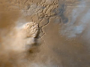 This image shows a turbulent mass of thick, roiling, red Martian dust rising from a network of canyons and flowing diagonally toward the lower left corner of the frame. Credit: NASA