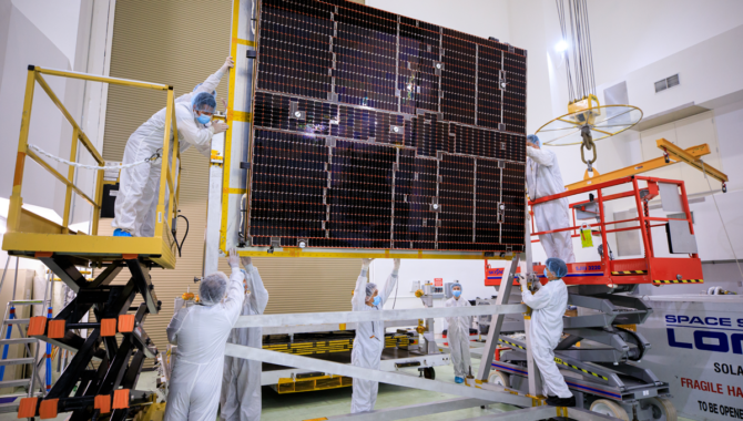 In this image from July 18, 2023, a NASA team helps attach solar arrays for the agency’s Psyche spacecraft onto a stand inside the Astrotech Space Operations Facility near Kennedy Space Center in Florida. Photo Credits: NASA/Isaac Watson