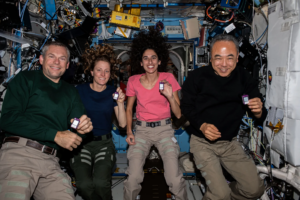 (From left) Expedition 70 Commander Andreas Mogensen of ESA (European Space Agency); and Flight Engineers Loral O’Hara and Jasmin Moghbeli, both from NASA; and Satoshi Furukawa of JAXA (Japan Aerospace Exploration Agency), pose for a portrait aboard the International Space Station’s Destiny laboratory module. The quartet is showing off crew active dosimeters that monitor the amount of radiation astronauts are exposed to in the microgravity environment. Photo Credit: NASA