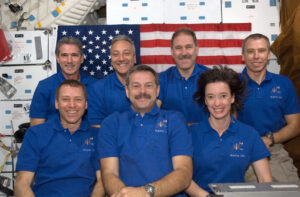 STS-125 crew members pose for a portrait in front of an American flag on Atlantis’ middeck. From left to right, back row: Mission Specialists Michael Good; Mike Massimino, John Grunsfeld, Andrew Feustel. From left to right, front row: STS-125 Pilot Gregory C. Johnson, STS-125 Commander Scott Altman, and Mission Specialist Megan McArthur. Photo Credit: NASA