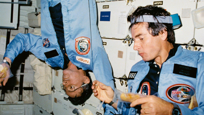 Commander John W. Young (left), and Payload Specialist Ulf Merbold, enjoy a meal in the middeck of the Earth-orbiting Space Shuttle Columbia during STS-9. Credit: NASA