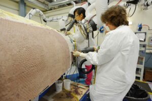 Technicians at Textron in Wimington, MA, apply Avcoat ablative material to the composite honeycomb structure attached to the Exploration Flight Test-1 (EFT-1) Orion heat shield carrier structure on May 22, 2013. Credit: NASA/Radislav Sinyak