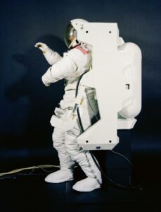 Side close-up view of crewman in high-fidelity Extravehicular Mobility Unit (EMU) / Manned Maneuvering Unit (MMU) mockup. Credit: NASA