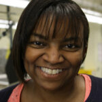 Paula Cain smiles at the camera. She has black hair just above her shoulder. She is a Black woman.