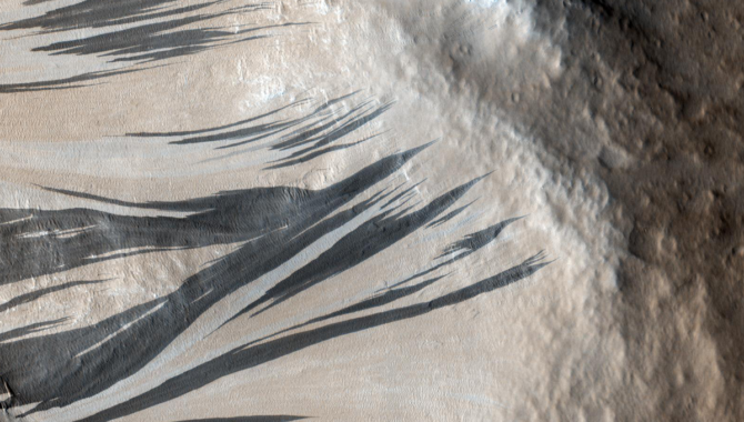 These dark streaks, also known as "slope streaks," are in an area of Mars known as Acheron Fossae. The source of these features is a topic of a recent machine learning research project. Credit: NASA