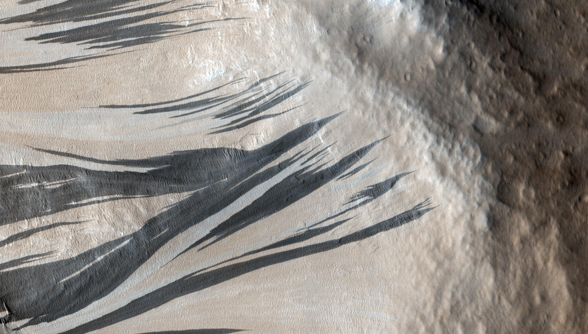 These dark streaks, also known as "slope streaks," are in an area of Mars known as Acheron Fossae. The source of these features is a topic of a recent machine learning research project. Credit: NASA