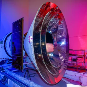 Spacecraft inside a facility. It has a conical shape with a shiny interior. The outer shell is white. Credit: NASA/JPL-Caltech