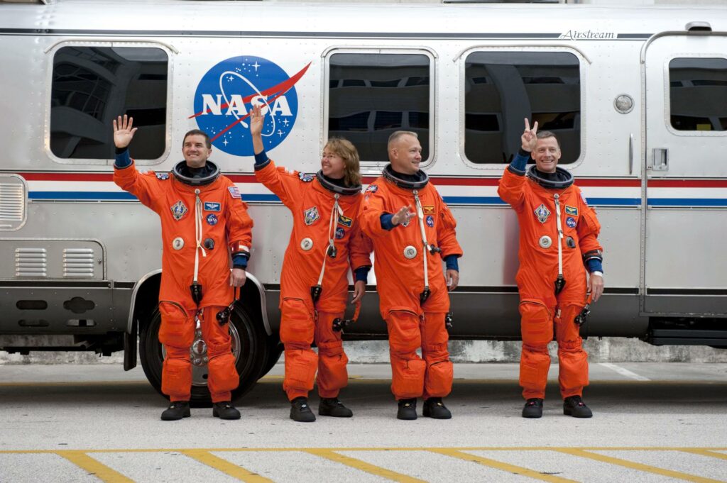 After suiting up, the crew of STS-135 paused to wave to onlookers before heading to the Space Shuttle Atlantis, which was waiting at launch complex 39A. From right are NASA astronauts Chris Ferguson, commander; Doug Hurley, pilot; and Sandy Magnus and Rex Walheim, both mission specialists. Credit: NASA
